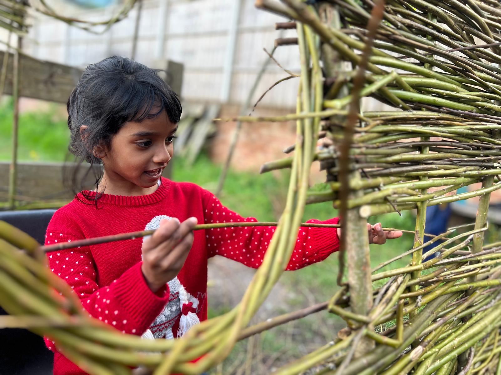 young girl weaving willow into a living fence